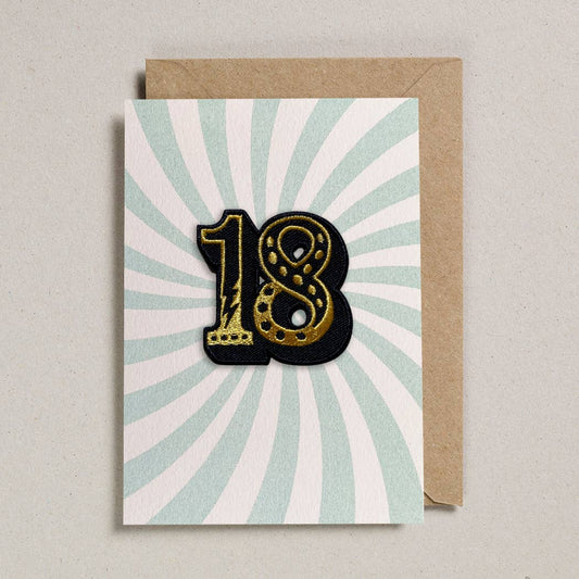 Greeting card with gold number '18' on a sunburst pattern, featuring a brown envelope.