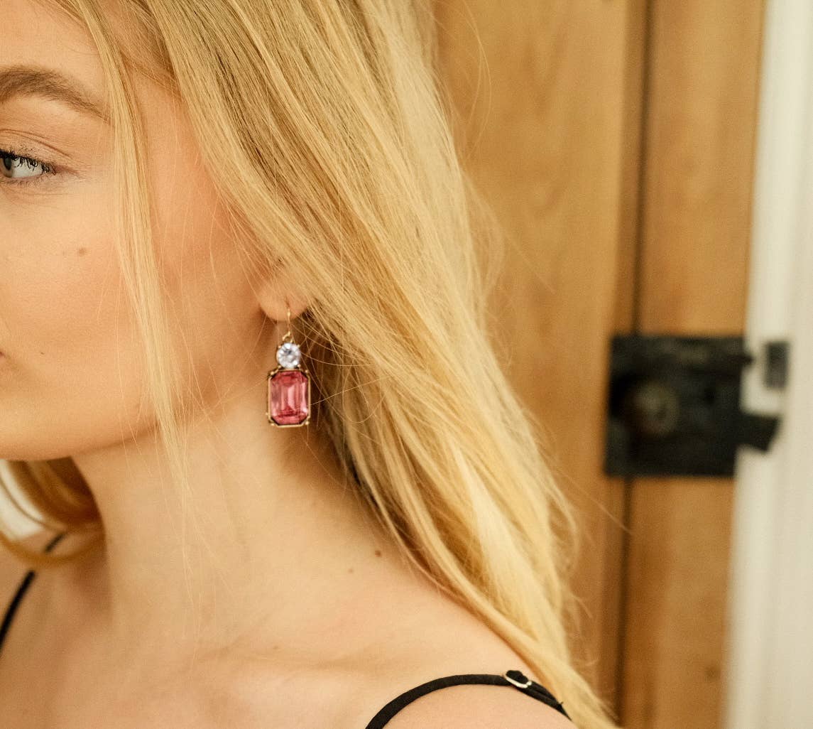 Close-up of a woman wearing pink gemstone earrings with a blurred background