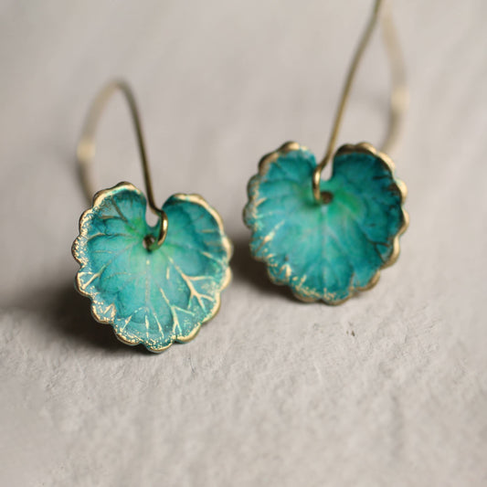 Pair of teal earrings with gold accents on a light gray background