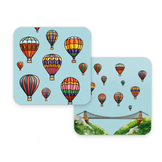 Two coasters with colorful hot air balloons and a bridge over water design on a light blue background.