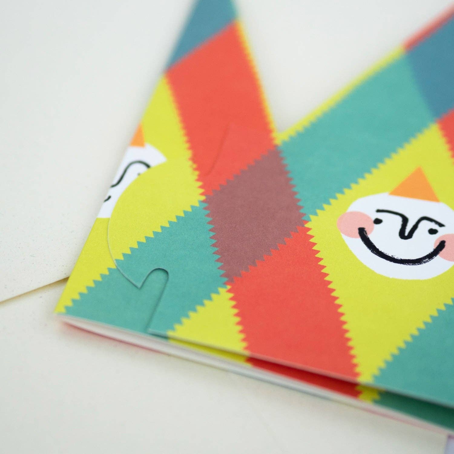 Colorful geometric-patterned notebook with a smiley face sticker on a white background
