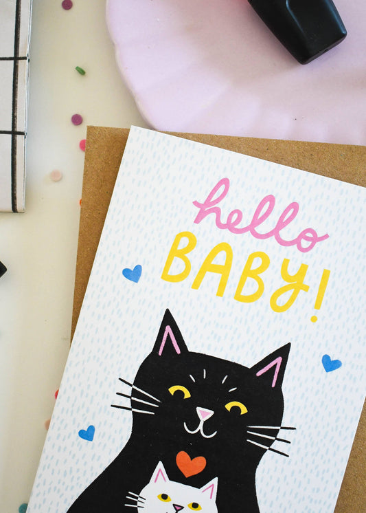 Greeting card with a black cat illustration and 'hello BABY!' text on a white background.