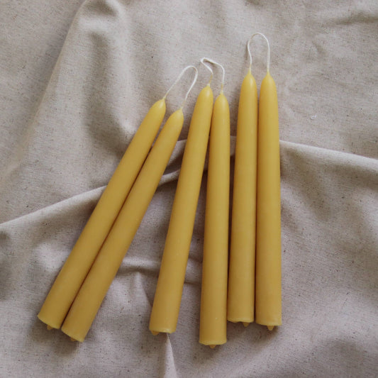 Five yellow candles on a beige fabric background