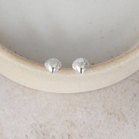 Silver shell-shaped earrings on a light-colored stone surface