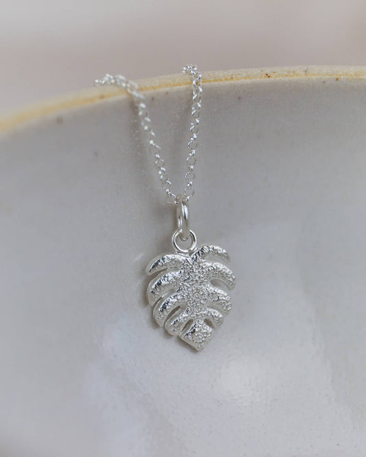 Silver leaf pendant necklace on a white dish