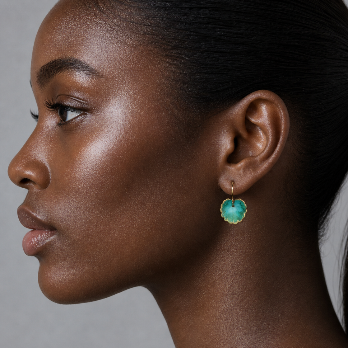 Close-up of a woman wearing a green earring against a neutral background