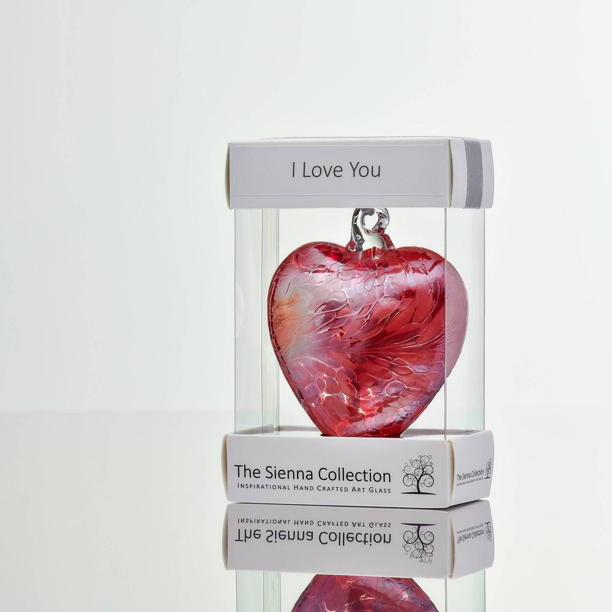 Glass heart in clear packaging on white background.