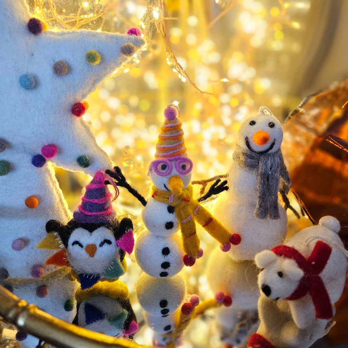 Decorative Christmas figures including snowmen and a penguin with string lights in the background.