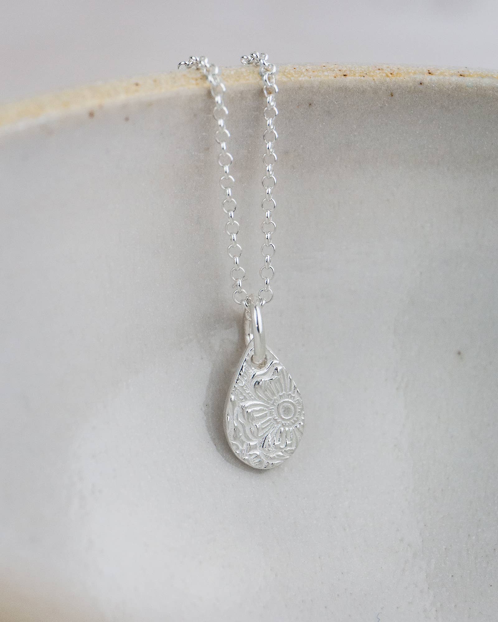 Silver teardrop pendant necklace on a light gray background
