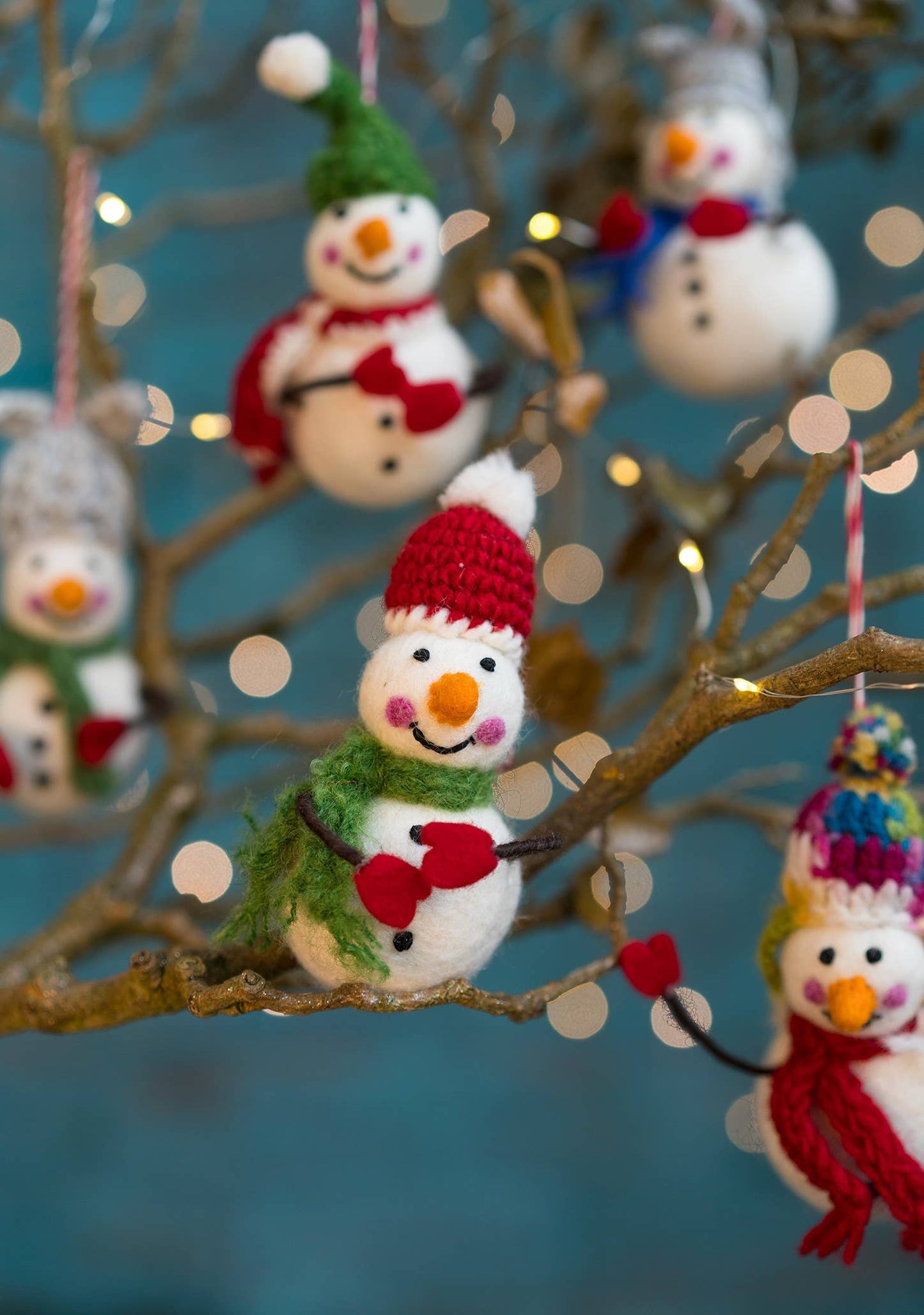 Felted snowman with colourful hat, scarf and bendy arms with mittens on.