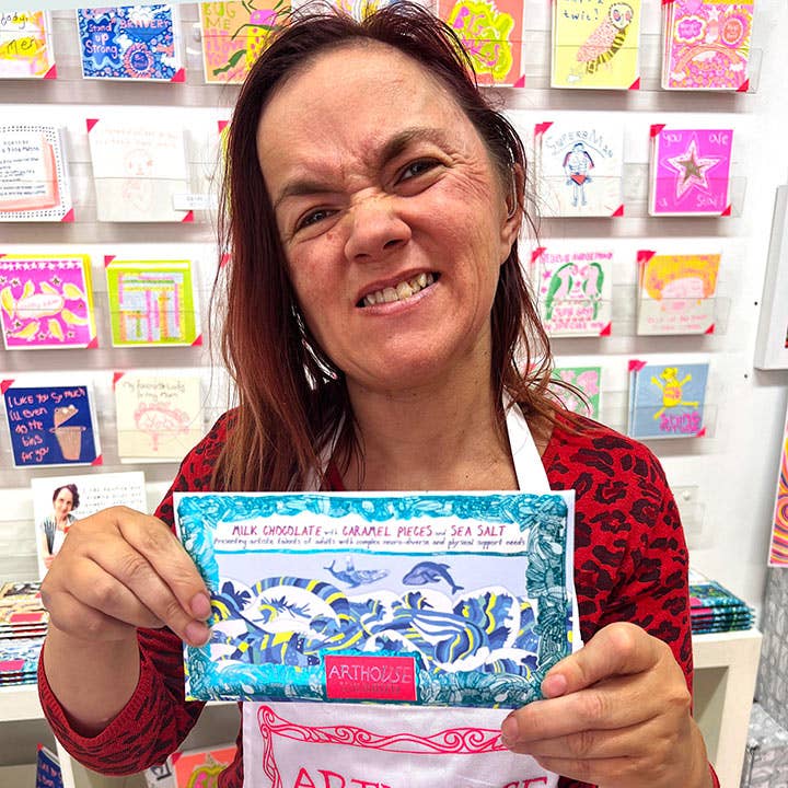 Woman holding a chocolate bar with a colorful background of cards
