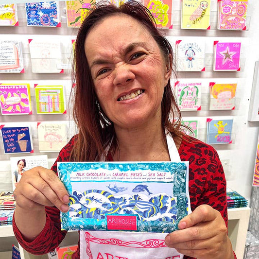 Woman holding a chocolate bar with a colorful background of cards