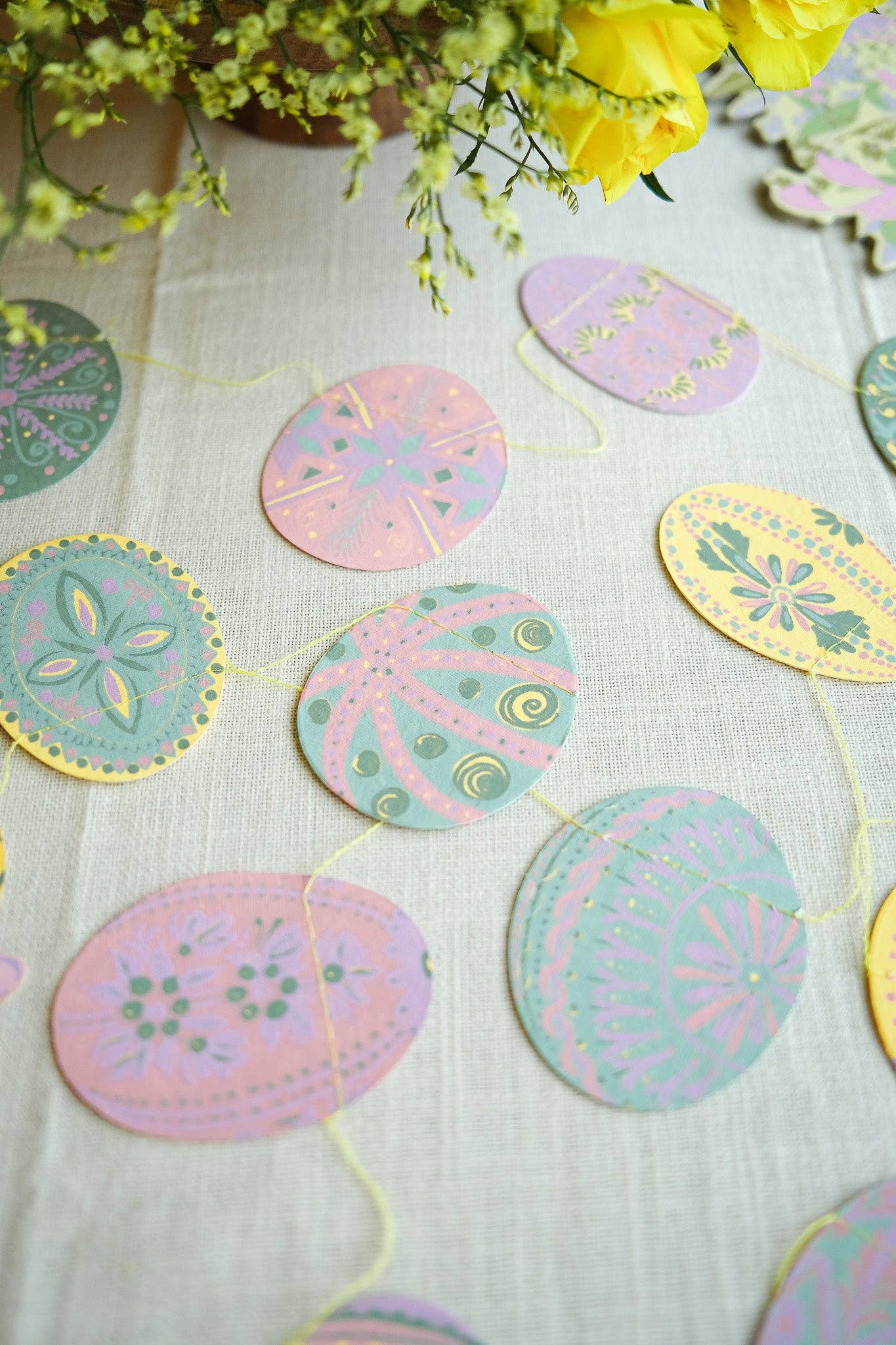 Decorative pastel-colored circular ornaments on a white fabric background with yellow flowers.