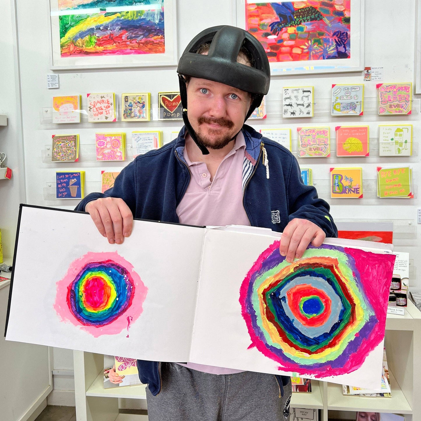 Person holding a drawing of a colorful spiral in an art store.