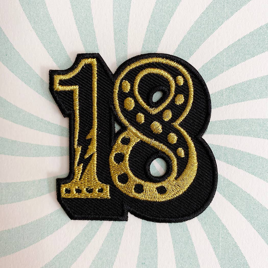 Gold and black embroidered number '18' patch on a striped background