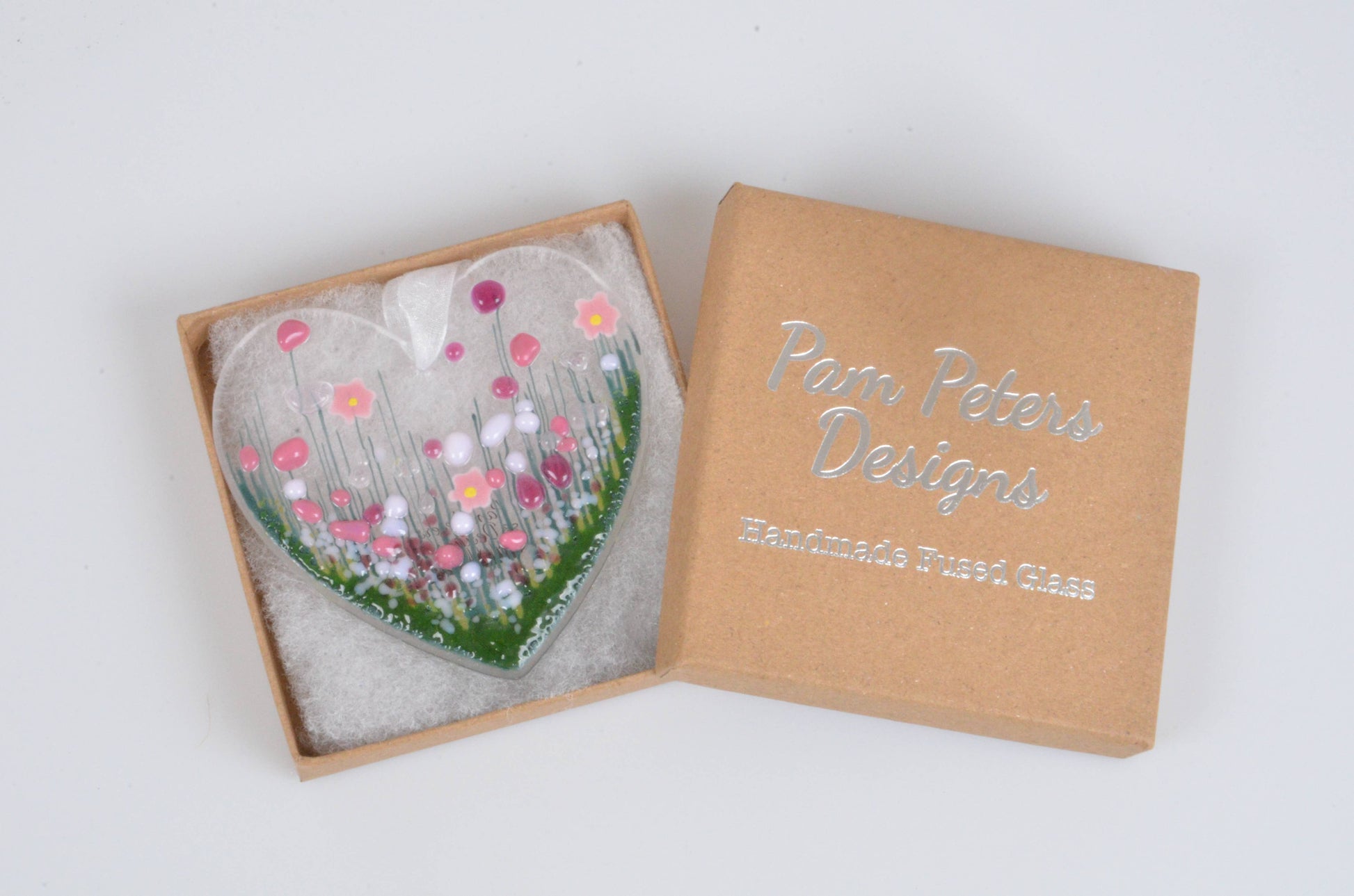 Heart-shaped glass piece with floral design in a branded box on a white background