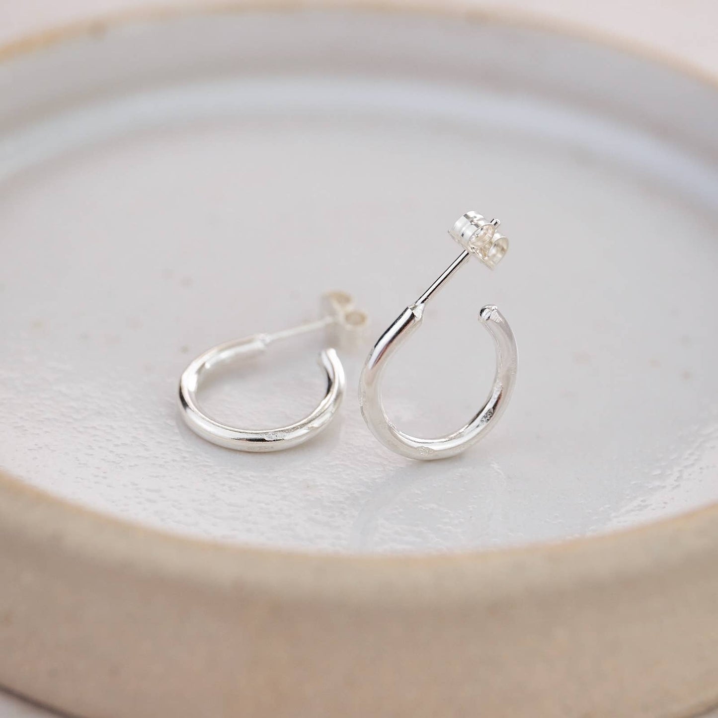 Silver hoop earrings on a light ceramic plate
