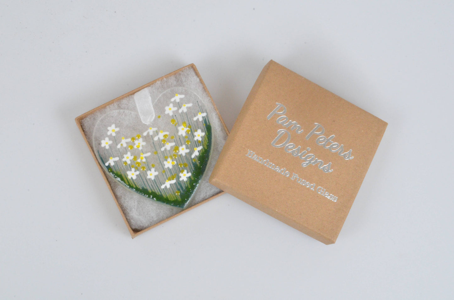 Glass flower arrangement in a cardboard box on a light gray background