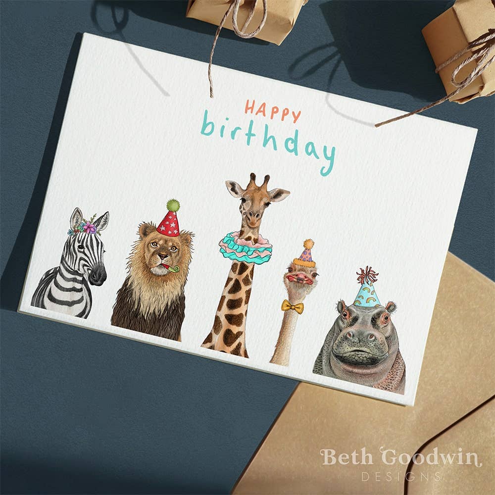 Birthday card with illustrated animals wearing party hats on a dark surface.