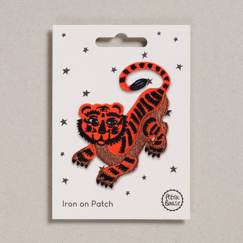 Orange and black tiger patch on a white card with star decorations