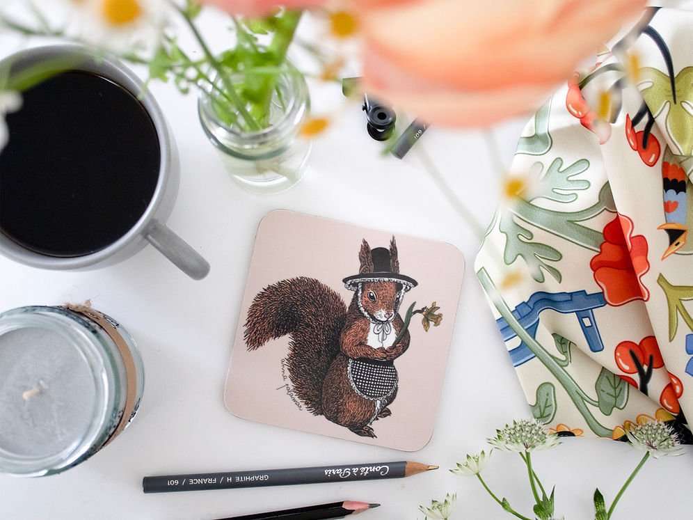 A square coaster with rounded corners featuring an illustration of a red squirrel wearing a black hat and a checkered apron, holding a daffodil.