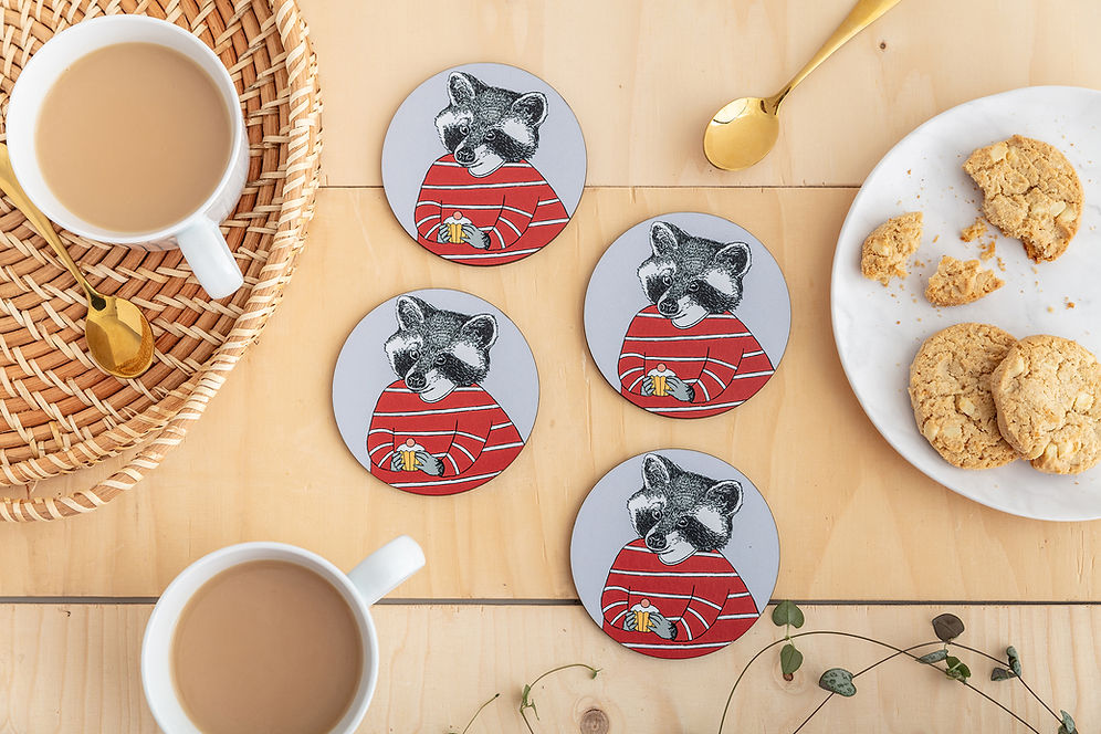 Four round coasters featuring an illustration of a raccoon in a red striped top, about to enjoy a little cake.