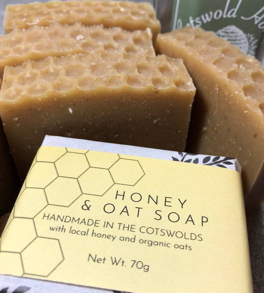 Honey and oat soap with packaging labeled 'Handmade in the Cotswolds' on a dark background.
