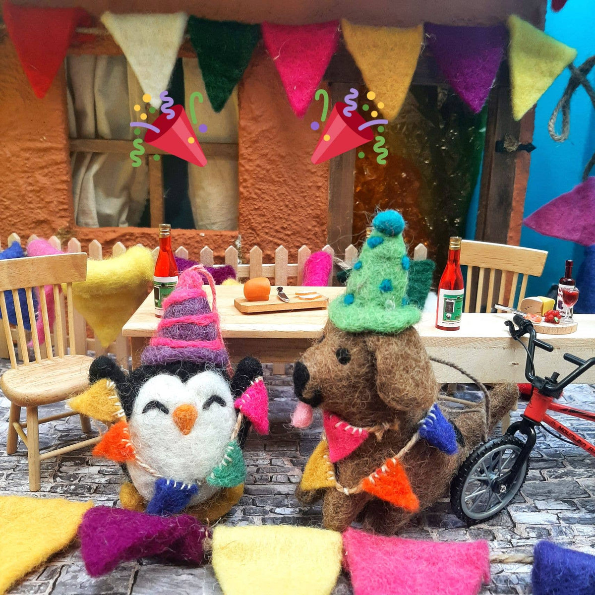 Two plush toys, a penguin and a bear, with festive hats in a colorful indoor setting.
