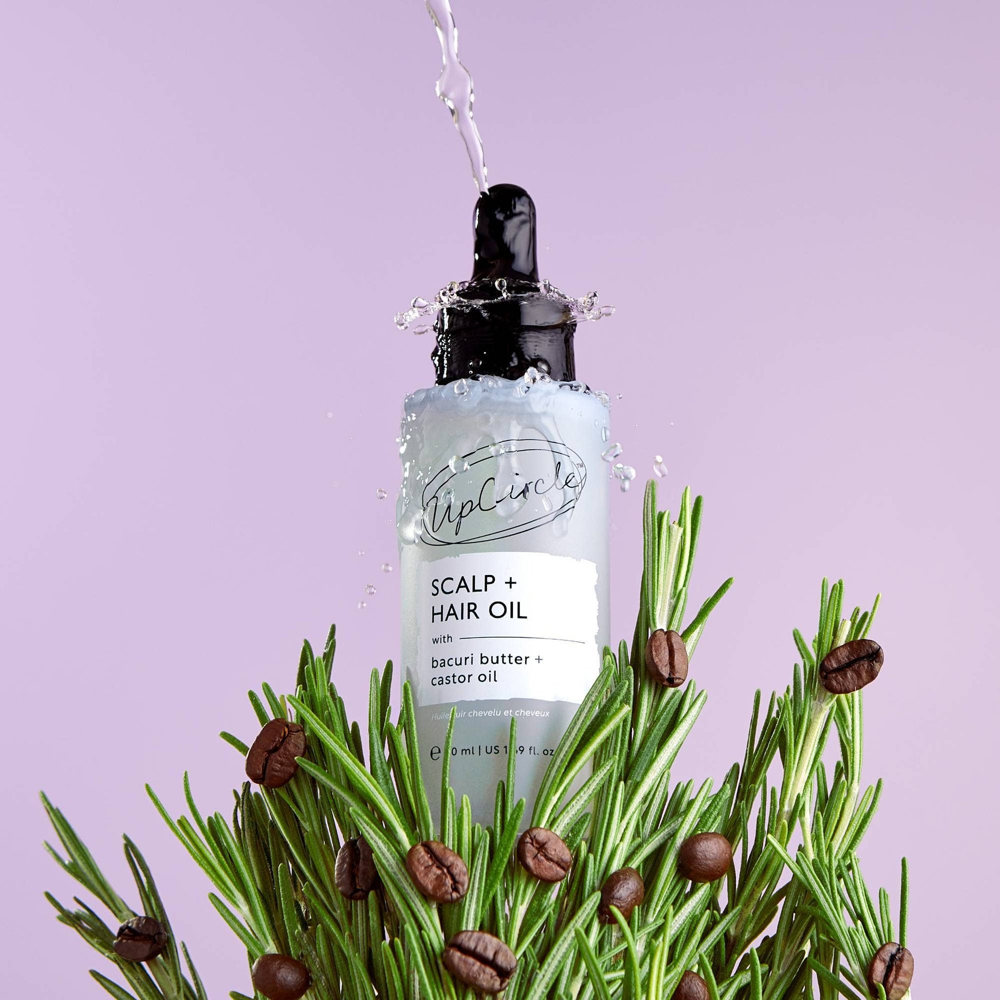 Bottle of scalp and hair oil with green leaves and coffee beans on a purple background
