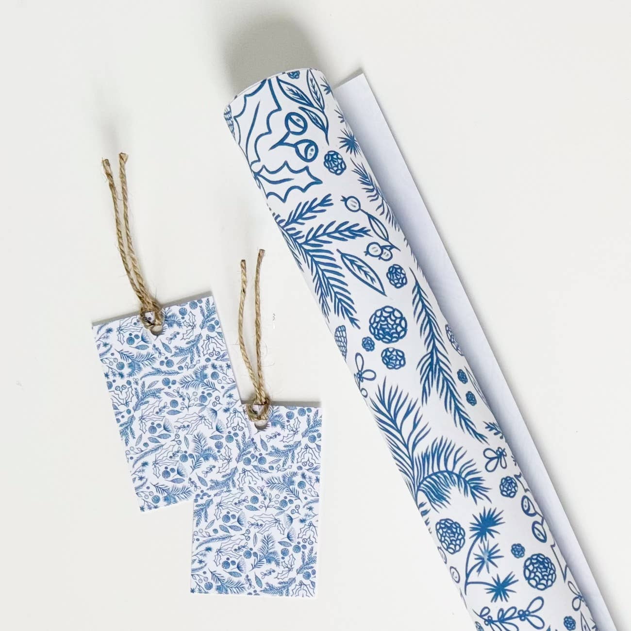 Blue on white gift wrap with festive foliage drawings.