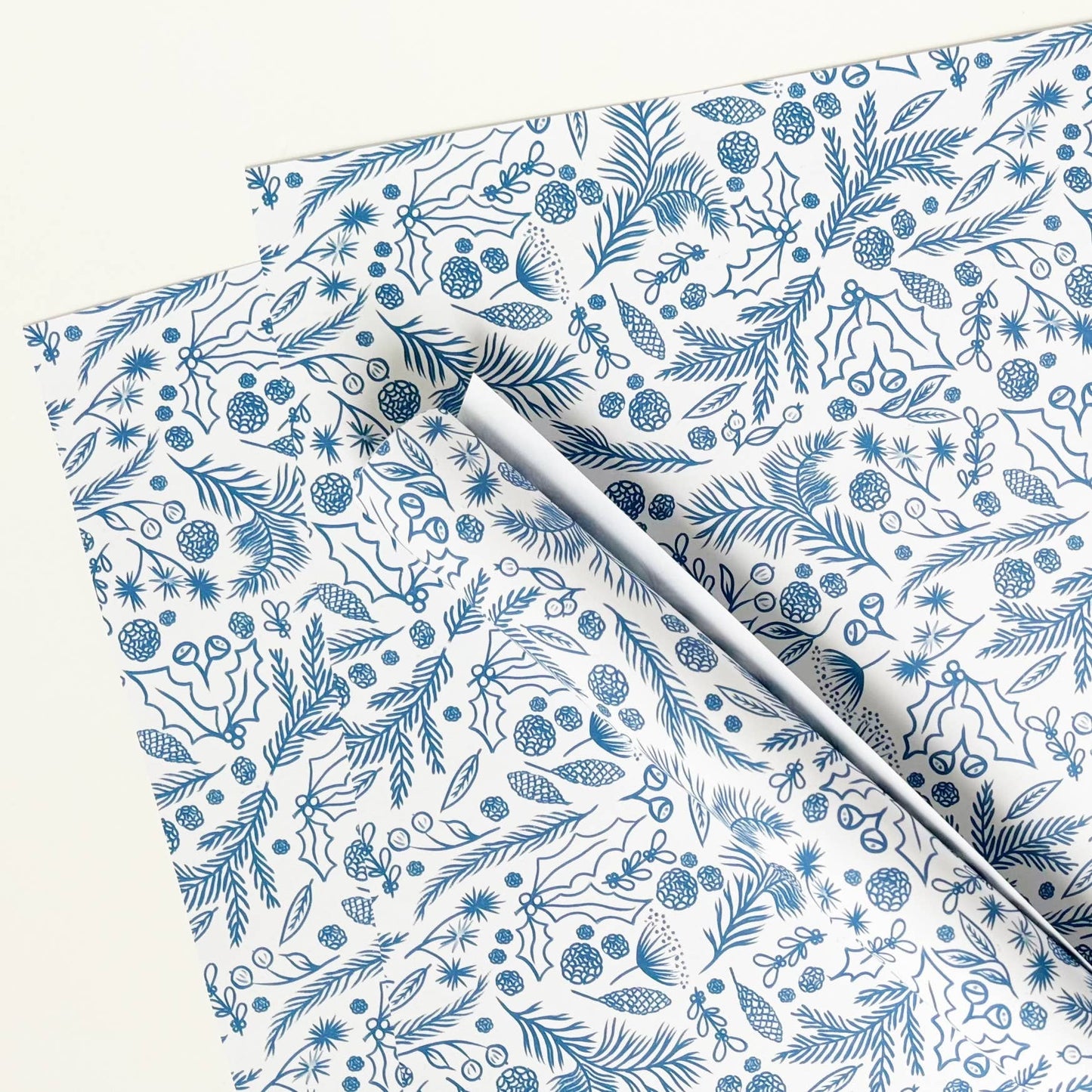 Blue on white gift wrap with festive foliage drawings.