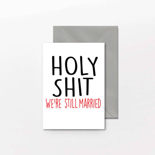 Card with text 'HOLY SHIT WE'RE STILL MARRIED' on a white background