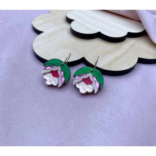 Floral earrings on a wooden cloud-shaped stand against a light purple background