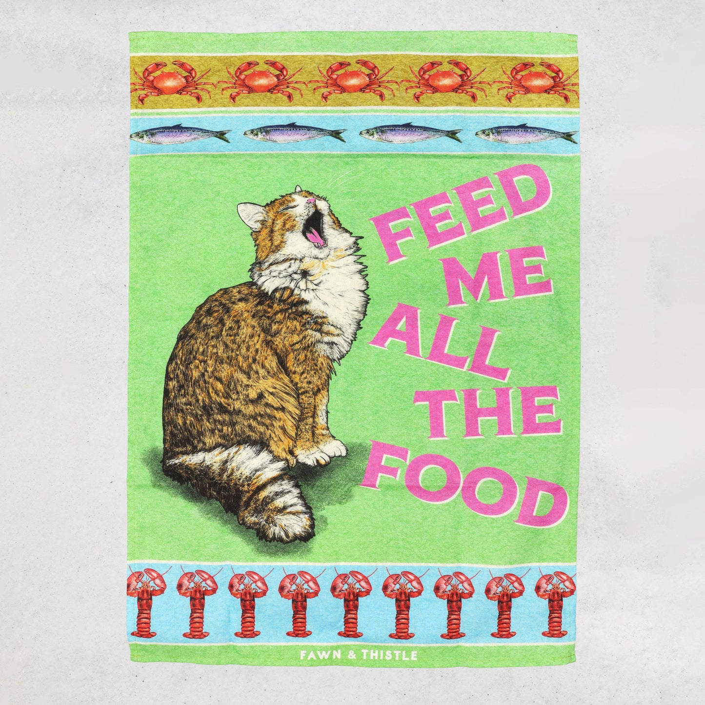 Tea towel with a cat illustration and text 'Feed Me All The Food' on a green background.