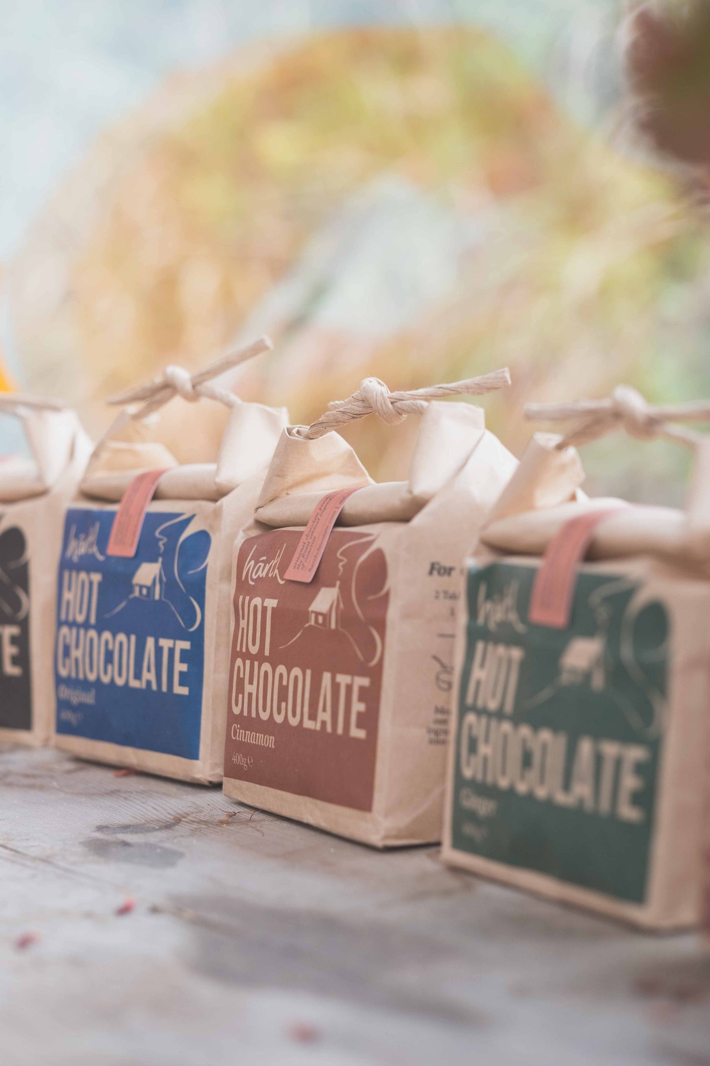 Three packages of hot chocolate with colorful labels on a wooden surface.