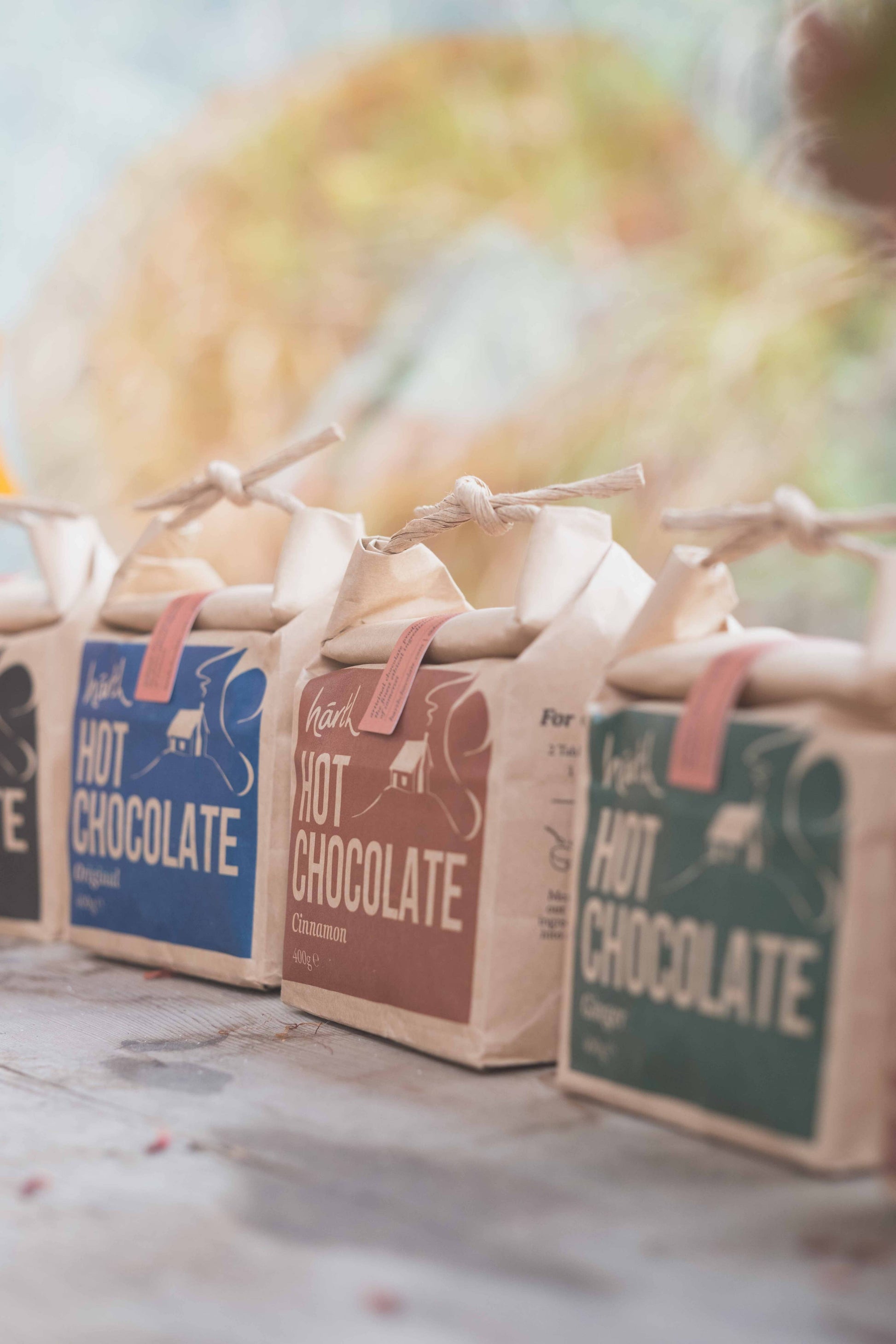 Three packages of hot chocolate with colorful labels on a wooden surface.