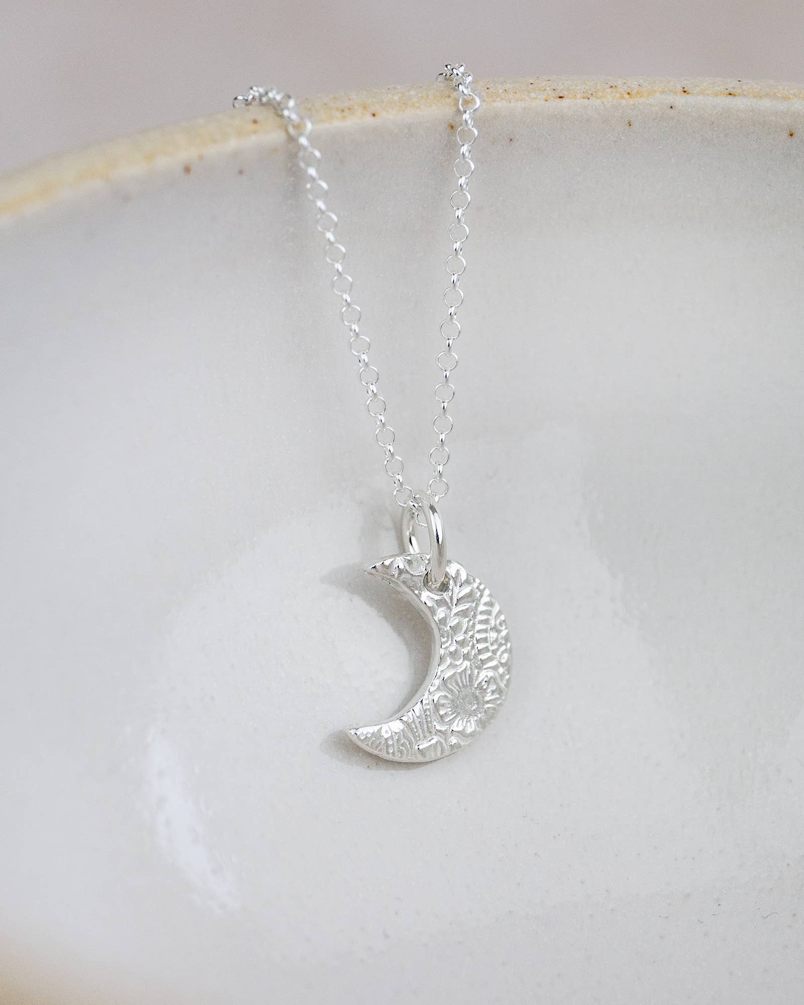 Silver crescent moon necklace on a light background