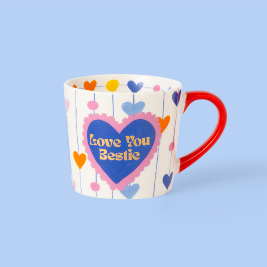 Mug with colorful heart design and 'Love You Bestie' text on a light blue background