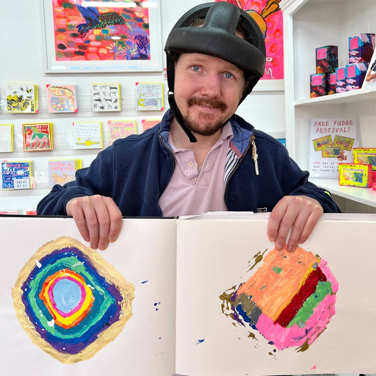 Man holding a book with colorful artworks in an art store