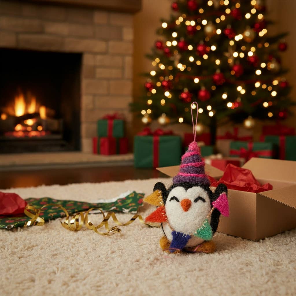 Decorative penguin ornament with a colorful hat and scarf in front of a Christmas tree and fireplace.