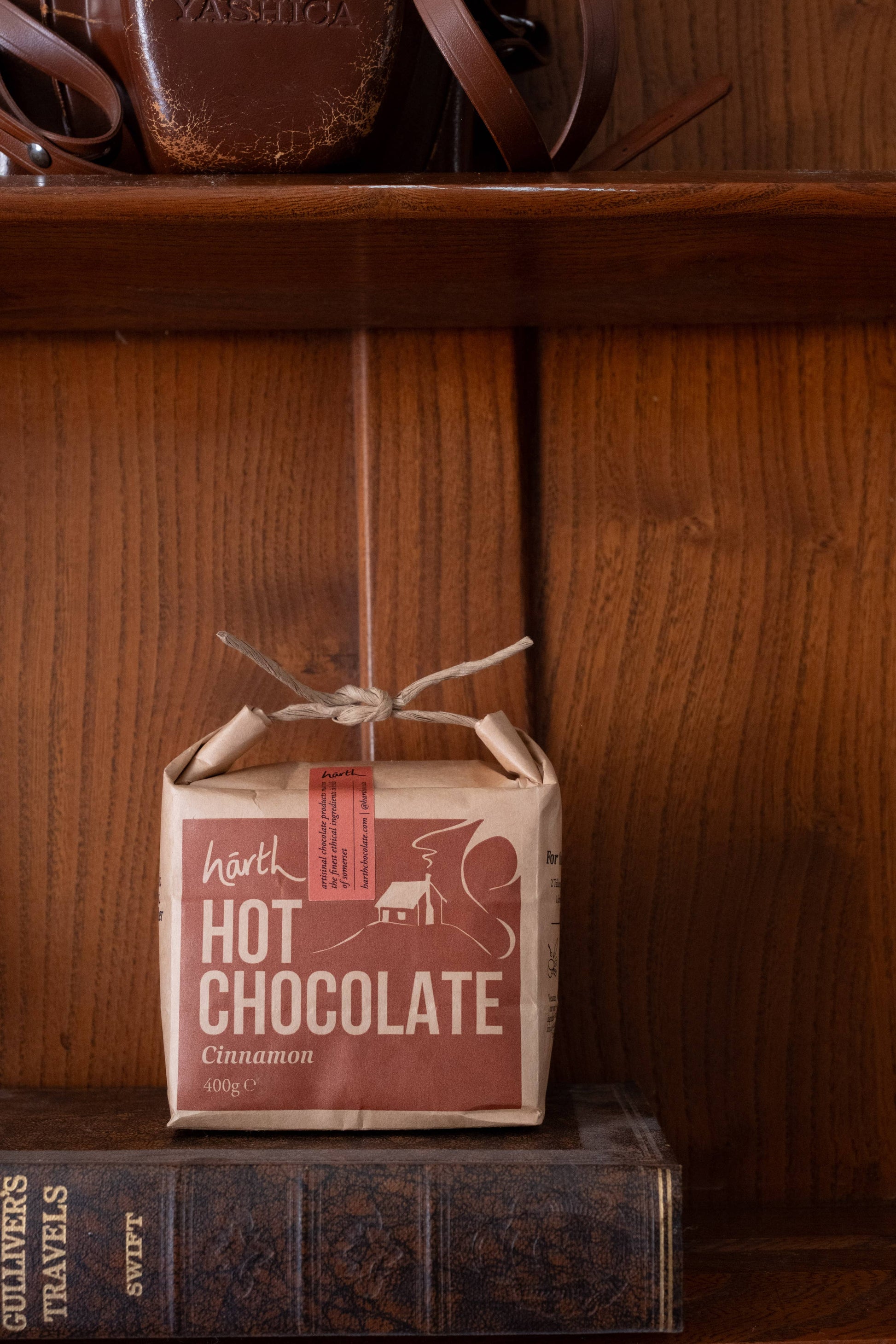 Box of Härth hot chocolate on a wooden shelf with a book below.