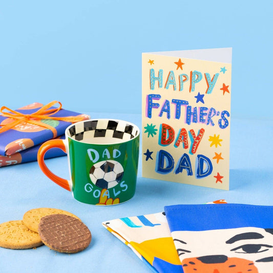 Mug with card, biscuits and tea towels on blue background.