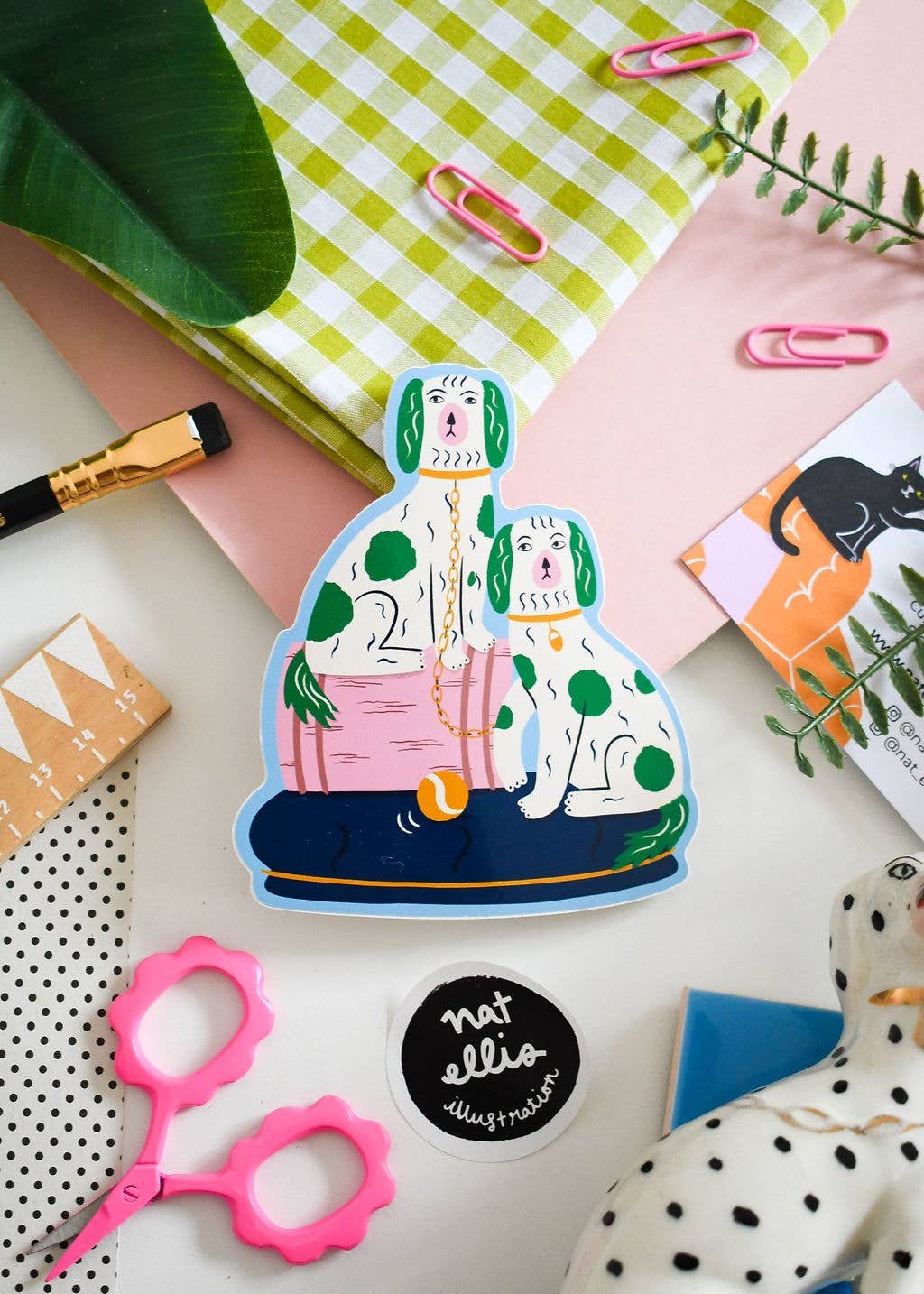 Colorful illustration of a woman with a dog on a flat surface with stationery items.