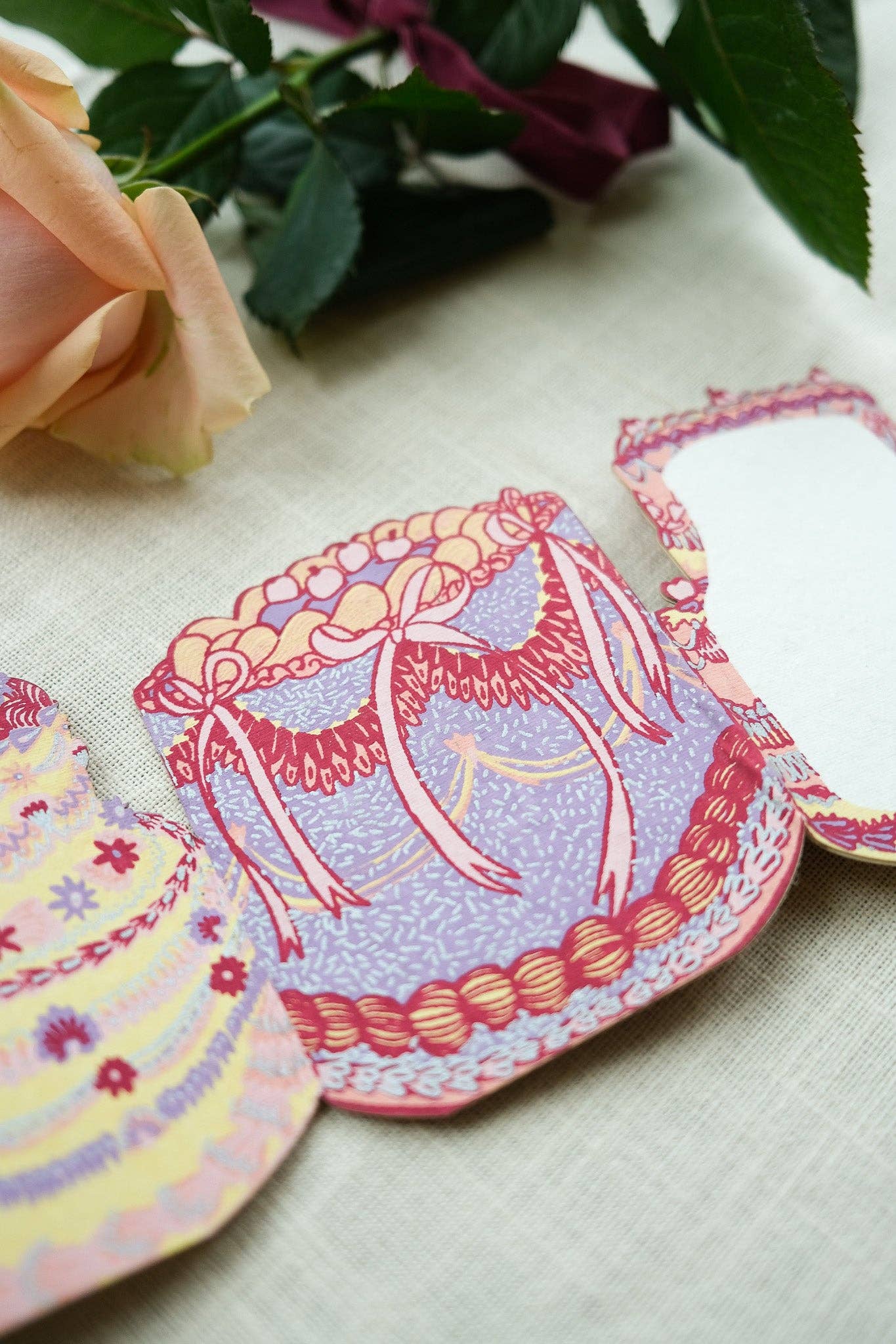 Colorful paper cutouts of dresses on a textured surface with flowers in the background