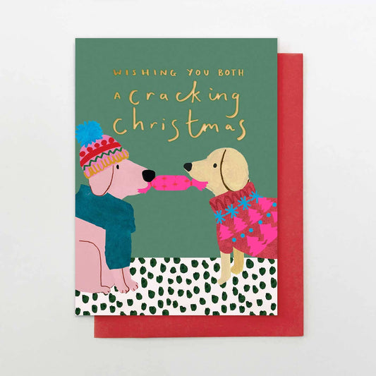 Christmas card with two dogs in winter clothing and a candy cane, on a green and red background.