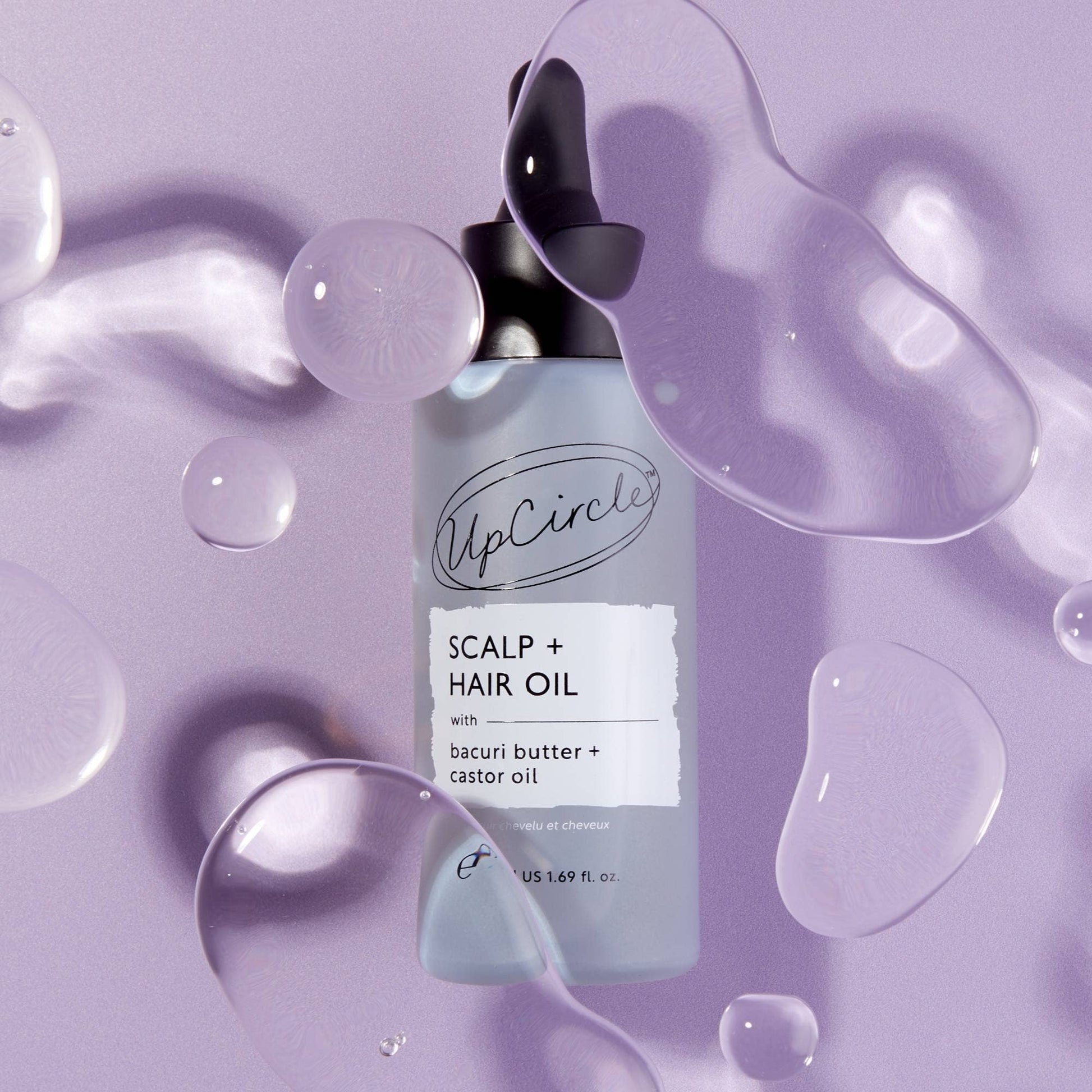 UpCircle Scalp + Hair Oil bottle on a purple background with oil droplets.