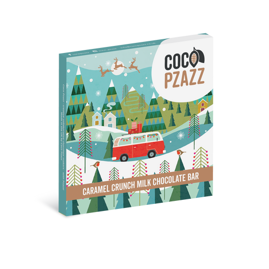A boxed chocolate bar product shown at a slight angle on a white background. The package features a colorful winter forest illustration with a red van, evergreen trees, snow, and the visible brand name 'COCO PZAZZ' in the upper right.
