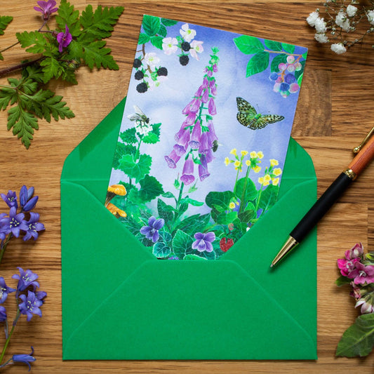 This card features a busy woodland floor scene of hand-painted acrylic illustrations. It includes a tall pink foxglove, wild strawberries and many bees, butterflies and crawlers. The pale blue-lilac watercolour background adds more depth to the scene. Around the foxglove, violets and cowslips you can spot a bright yellow Brimstone Butterfly, a large speckled Fritillary Butterfly and even a snail peaking through the leaves. The card is fully printed back to front and is like a little piece of art.