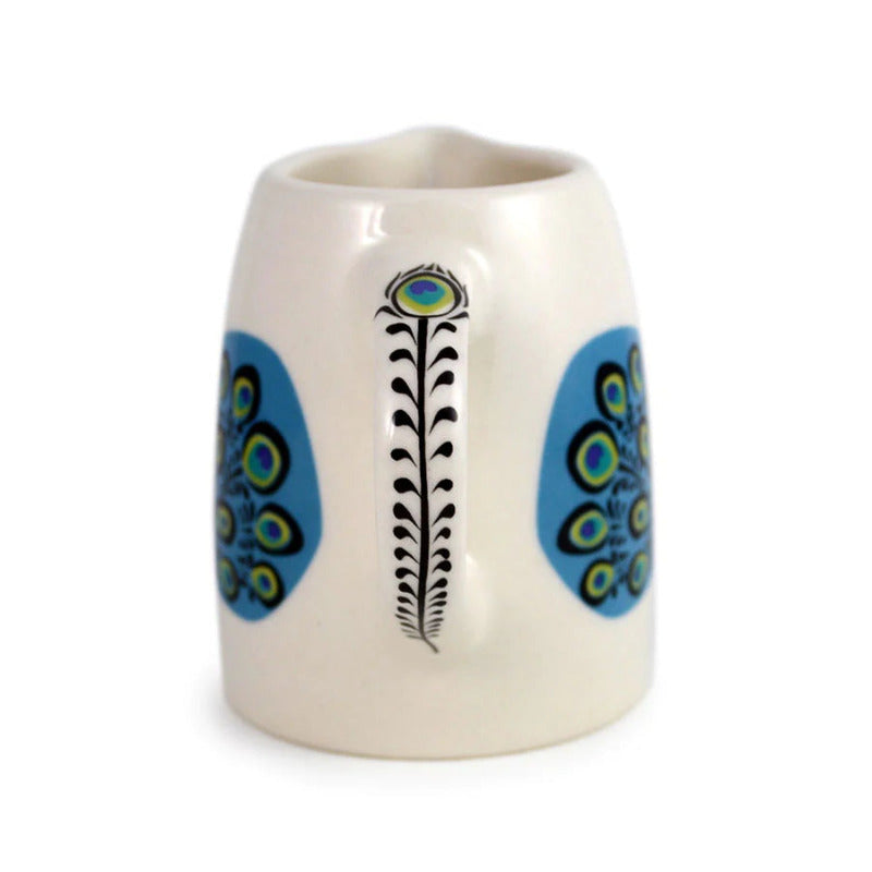 Small white ceramic jug with blue green and yellow folk art style peacock design