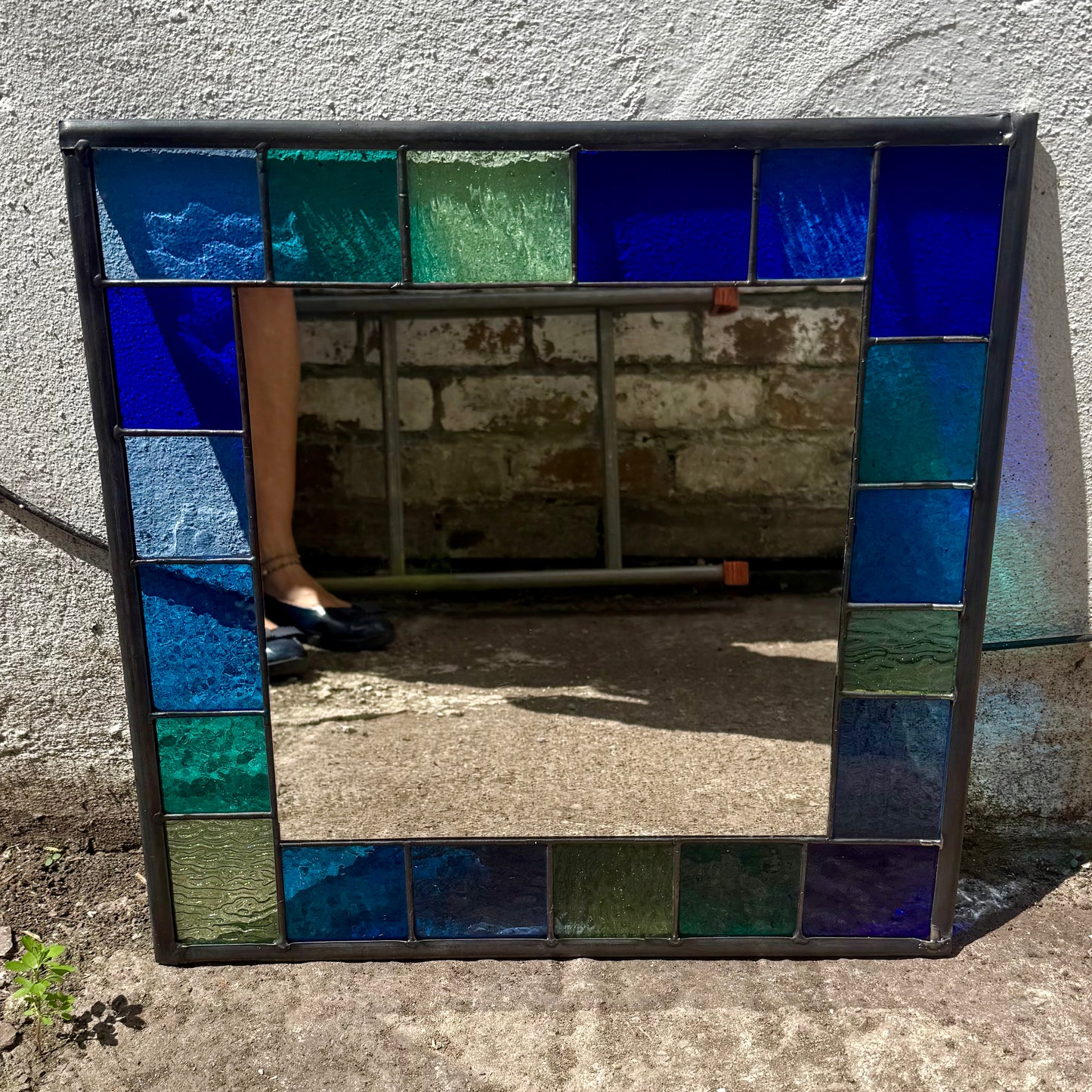 Square stained glass mirror with a 6cm border of greens, blues and aqua colours.